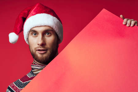 handsome man in a santa hat holding a banner holiday red backgroundの写真素材
