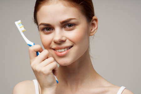 pretty woman with a toothbrush in hand morning hygiene light backgroundの写真素材