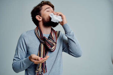 cold man in a sweater with a handkerchief infection light backgroundの写真素材