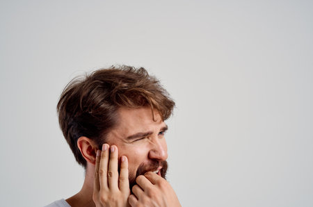 bearded man holding on to face pain in teeth isolated backgroundの写真素材