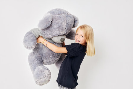 happy cute girl with teddy bear a toy on a light backgroundの写真素材