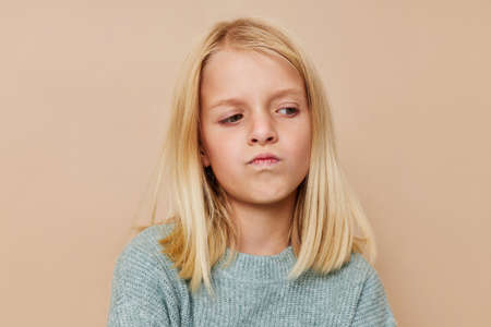Beautiful little girl in a sweater, grimaces cropped viewの写真素材
