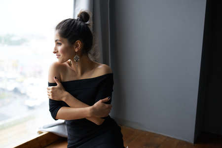 beautiful woman near window posing attractive look earrings fashion modelの写真素材