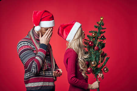 cute man and woman new year tree decoration holiday red backgroundの写真素材