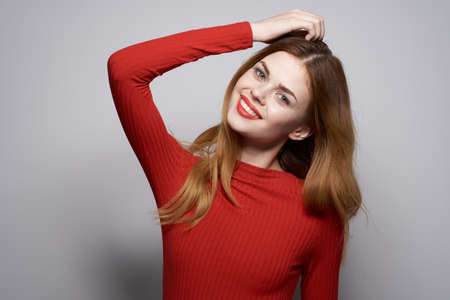 pretty woman fashion hairstyle red sweater model light backgroundの写真素材