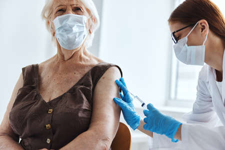 elderly woman with a doctor syringe with vaccine health careの写真素材