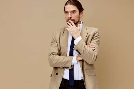 man in beige jacket emotional man in suit gesture with hands beige backgroundの写真素材