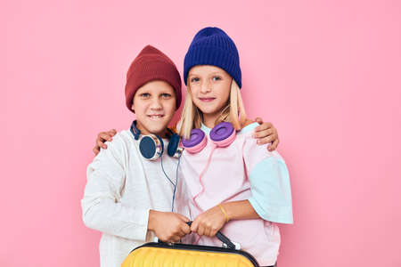 joyful boy and girl stylish clothes suitcase headphones studio posingの写真素材