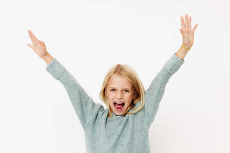 Little cute girl in a sweater, grimaces on a light backgroundの写真素材