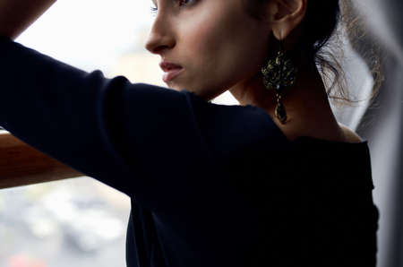 brunette near window posing attractive look earrings elegant style
