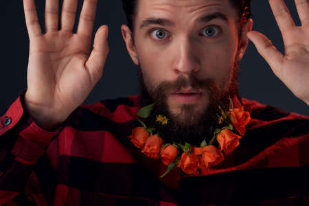 bearded man with flowers in a beard in a plaid shirt dark background