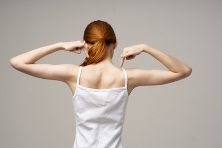woman in white t-shirt holding on to the neck health problems joint studio treatmentの写真素材