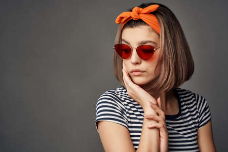woman in sunglasses with an orange bandage on her head in a striped t-shirt fashionの写真素材