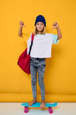 schoolgirl rides a skateboard with a red backpack Childhood lifestyle conceptの写真素材