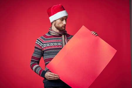 emotional man in a santa hat holding a banner holiday red backgroundの写真素材
