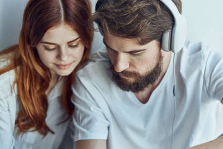 Man and woman sit near the window with headphonesの写真素材