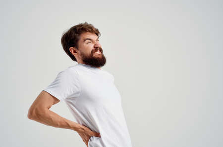 emotional man holding back arthritis health problems light backgroundの写真素材