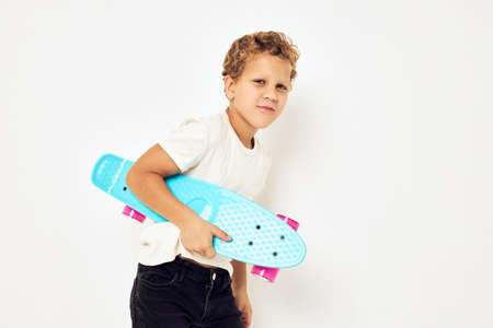 Portrait of young smiling kid curly hair with skateboard light background