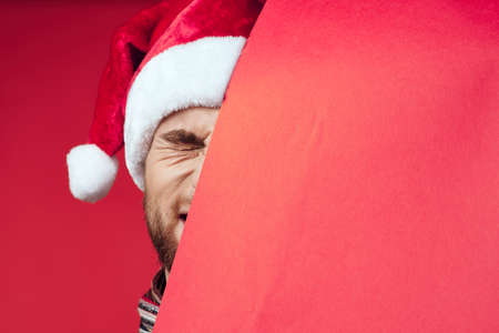 Cheerful man in a santa hat holding a banner holiday red backgroundの写真素材