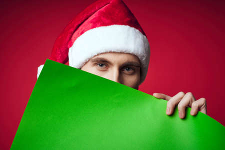 Cheerful man in a santa hat holding a banner holiday red backgroundの写真素材