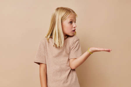 happy cute girl with blond hair on a beige backgroundの写真素材