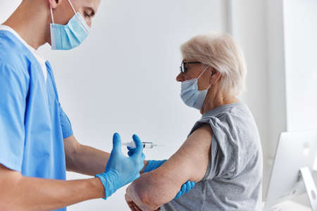 elderly woman next to the doctor arm injection vaccine passport immunization safetyの写真素材