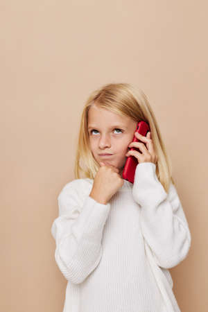 Beautiful little girl communication smartphone entertainment posing studioの写真素材