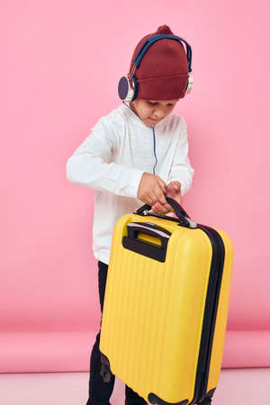 boy with yellow suitcase in hands fashion pink backgroundの写真素材