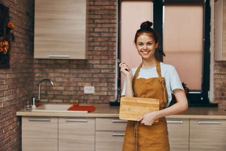 cheerful woman houses in the kitchen cutting board with knife apartments unalteredの写真素材