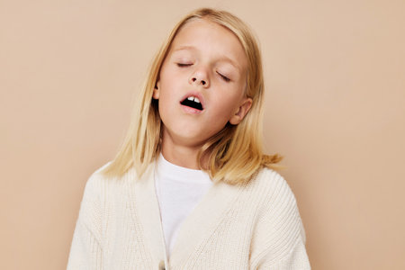 happy child in a sweater, grimaces on a beige backgroundの写真素材