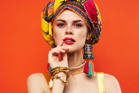 cheerful woman in multicolored turban attractive look Jewelry red backgroundの写真素材