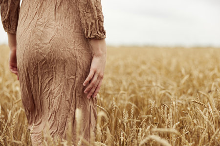 Woman hands the farmer concerned the ripening of wheat ears in early summer endless fieldの写真素材