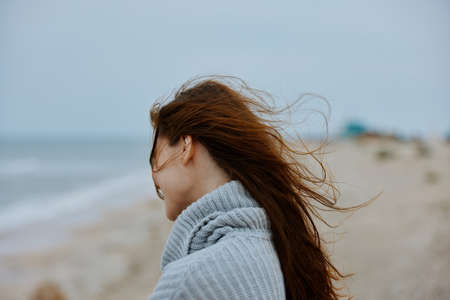 woman in a sweater flying hair by the ocean tourism unalteredの写真素材