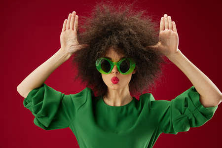 emotional woman gesturing with her hands afro hairstyle green glasses