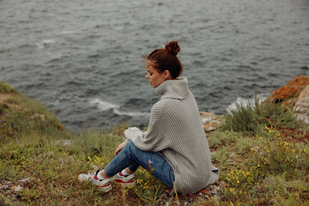 portrait of a woman in a gray sweater stands on a rocky shore nature unalteredの写真素材