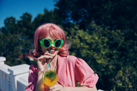 Delighted young girl in green sunglasses with cocktail in summer outdoors Drinking alcohol