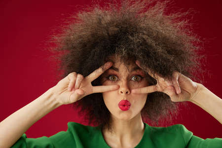 Young woman grimace afro hairstyle red lips fashion red background unaltered