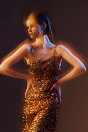young woman in a shiny dress posing luxury isolated background