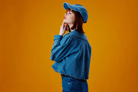 Positive young woman denim clothing fashion posing cap color background unalteredの写真素材