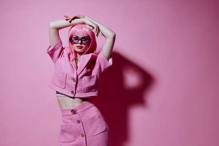 Young positive woman pink suit sunglasses posing pink background unalteredの写真素材