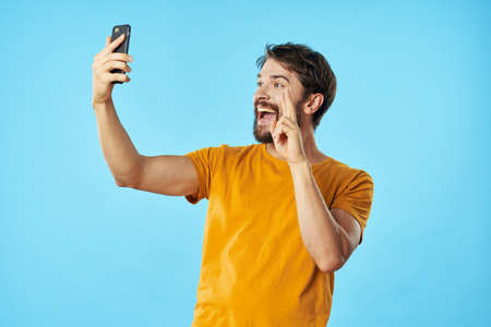 man in yellow t-shirt with a phone in his hands blue technology background