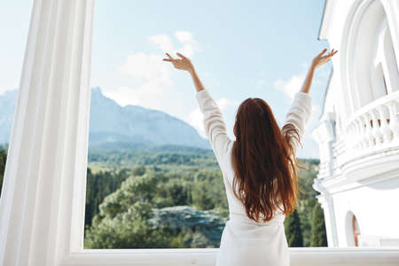 beautiful woman hands up on the balcony back viewの写真素材
