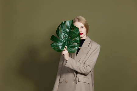 blonde woman green palm leaf coat bright makeup studio model unalteredの写真素材