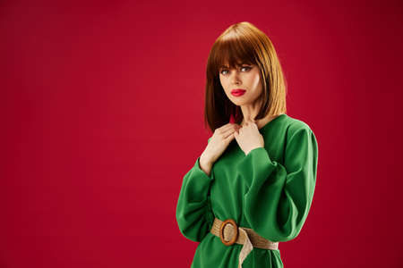 red-haired woman with red lips in a green dress red background