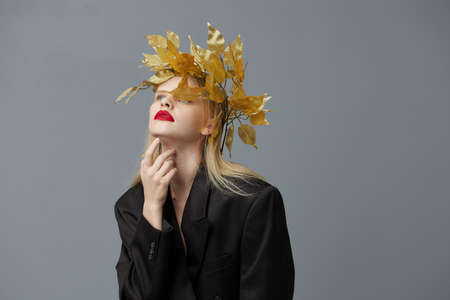 glamorous woman golden leaves on the head in black jacket studio model unalteredの写真素材