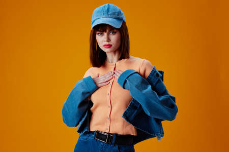Pretty young female denim clothing fashion posing cap color background unalteredの写真素材