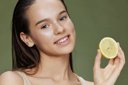 beautiful woman lemon in hands posing clean skin green backgroundの写真素材