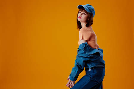 Pretty young female in a cap and denim jacket posing color background unaltered
