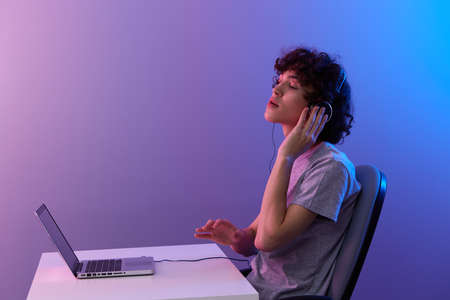 guy cyberspace playing with headphones in front of a laptop violet background