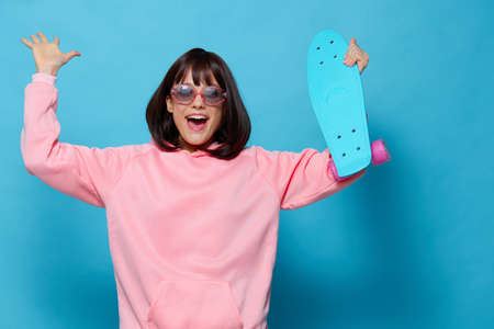 woman in a pink sweater skateboard entertainment blue backgroundの写真素材